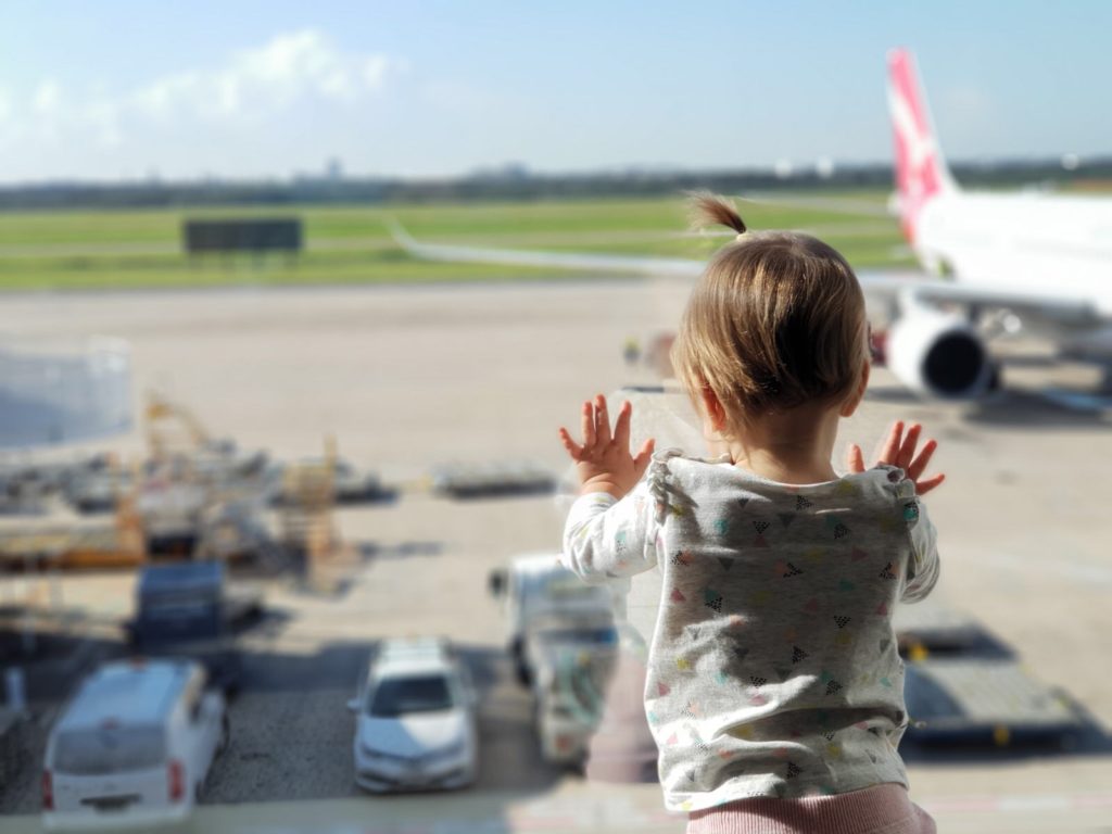 Little girl dressed in pink looking at the planes at the airport in New Zealand.