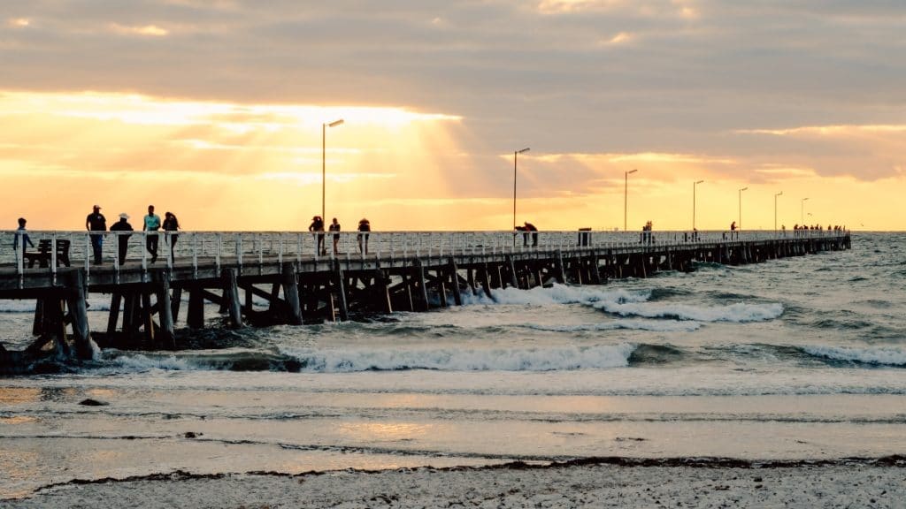 Jetty over the water at sunset time with people walking on it in Semaphore Adelaide Australia.